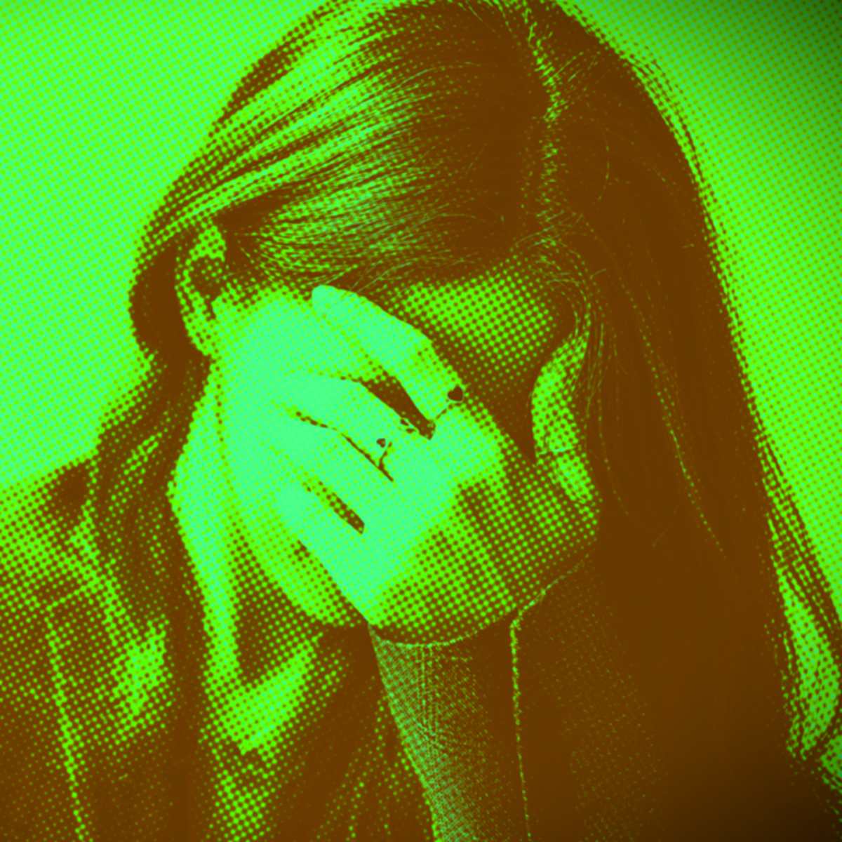 Mulher esconde o rosto com a mão, aparentando tristeza